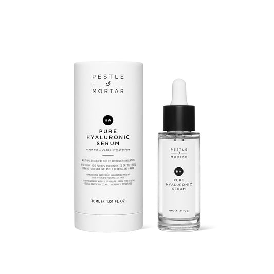 a glass bottle of pure hyaluronic serum from pestle & mortar next to its cylindrical outer packaging